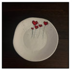 A touch of loveThis is a charming and simple piece of pottery. The white base and delicate red hearts create a clean and elegant look. The subtle speckles add a touch of texture and interest