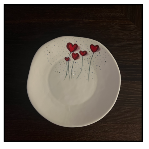 A touch of loveThis is a charming and simple piece of pottery. The white base and delicate red hearts create a clean and elegant look. The subtle speckles add a touch of texture and interest